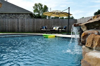 Modelo de piscina con fuente natural exótica de tamaño medio tipo riñón en patio trasero con entablado