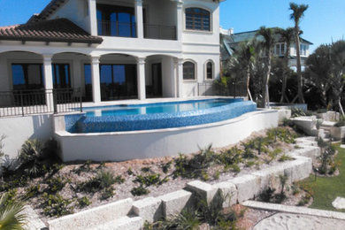 Réalisation d'une grande piscine hors-sol et arrière design sur mesure avec un bain bouillonnant et des pavés en pierre naturelle.