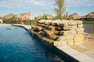 Foto de piscina con fuente natural exótica a medida en patio trasero con adoquines de piedra natural
