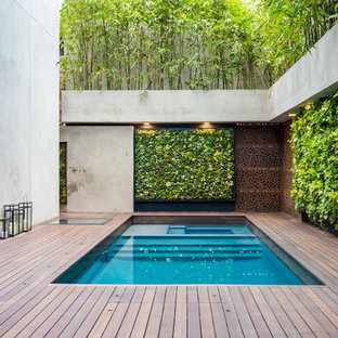 Immagine di una piscina design rettangolare in cortile con una vasca idromassaggio e pedane