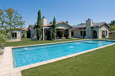 Foto de piscina con fuente mediterránea grande rectangular en patio trasero con adoquines de hormigón