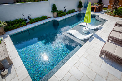 Modelo de piscina con fuente alargada actual de tamaño medio a medida en patio trasero con adoquines de hormigón