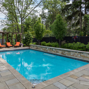 Photo of a mid-sized traditional backyard rectangular lap pool in Cleveland with a water feature and natural stone pavers.