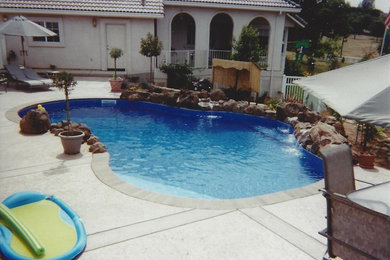 Diseño de piscina con fuente natural mediterránea a medida en patio con suelo de hormigón estampado
