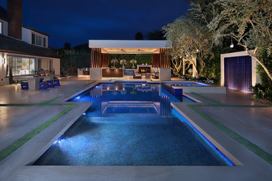 Example of a large trendy backyard stone and rectangular pool design in Orange County