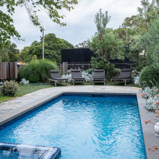 This is an example of a transitional rectangular pool in Melbourne with a hot tub and natural stone pavers.