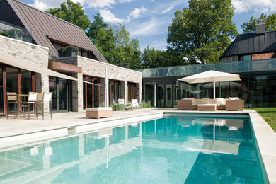 Imagen de casa de la piscina y piscina natural contemporánea grande rectangular en patio trasero con adoquines de piedra natural