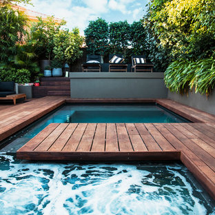 This is an example of a tropical backyard custom-shaped lap pool in Perth with a hot tub and decking.