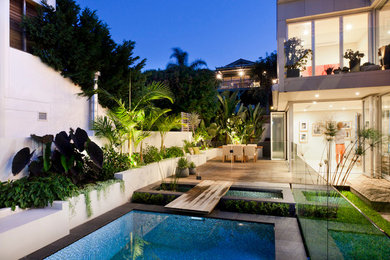 Diseño de piscina con fuente alargada actual de tamaño medio rectangular en patio trasero con entablado
