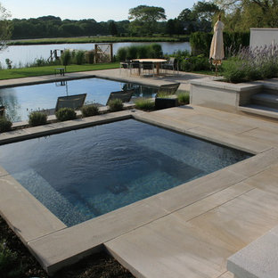 Ejemplo de piscinas y jacuzzis alargados, actuales, de tamaño medio, rectangulares, en patio trasero, con adoquines de piedra natural