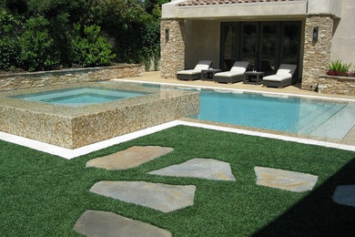 На фото: прямоугольный бассейн-инфинити среднего размера на заднем дворе в современном стиле с джакузи и покрытием из каменной брусчатки с