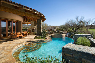 Ispirazione per una piscina naturale stile americano personalizzata di medie dimensioni e dietro casa con una vasca idromassaggio e pavimentazioni in pietra naturale
