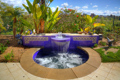 Esempio di una piscina mediterranea di medie dimensioni e dietro casa con una vasca idromassaggio e pavimentazioni in pietra naturale