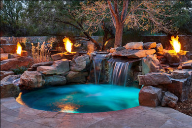 Ejemplo de piscinas y jacuzzis tradicionales de tamaño medio redondeados en patio trasero con adoquines de piedra natural