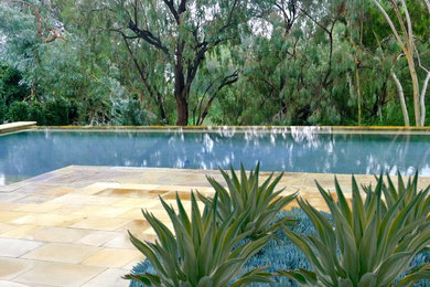 Example of a mid-sized minimalist backyard stone and rectangular infinity pool design in Los Angeles