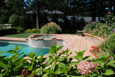 Esempio di una piscina stile americano rotonda con una vasca idromassaggio