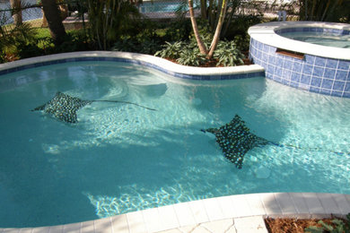 Réalisation d'une piscine naturelle et arrière tradition de taille moyenne et sur mesure avec un bain bouillonnant et des pavés en béton.