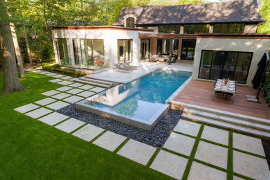 Großer Moderner Infinity-Pool hinter dem Haus in rechteckiger Form mit Wasserspiel und Natursteinplatten in Sonstige