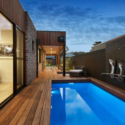 Example of a large minimalist side yard rectangular natural pool landscaping design in Other with decking