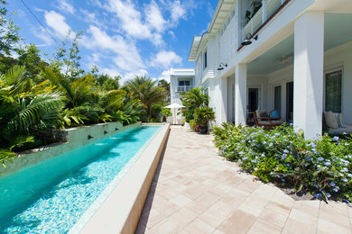 Exempel på en mellanstor modern rektangulär pool på baksidan av huset, med naturstensplattor
