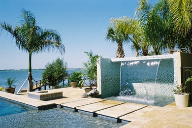 Imagen de piscina actual de tamaño medio a medida en patio trasero con adoquines de piedra natural