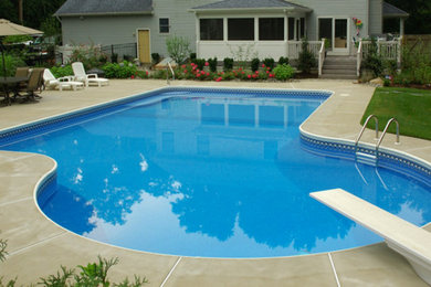 Foto de piscina alargada grande rectangular en patio trasero con losas de hormigón