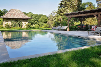 Imagen de piscina con fuente alargada de estilo americano grande rectangular en patio trasero con adoquines de hormigón