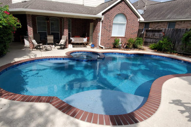 Hot tub - mid-sized traditional backyard stamped concrete and custom-shaped lap hot tub idea in Houston