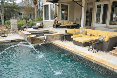 Modelo de piscinas y jacuzzis tradicionales extra grandes rectangulares en patio trasero con adoquines de piedra natural