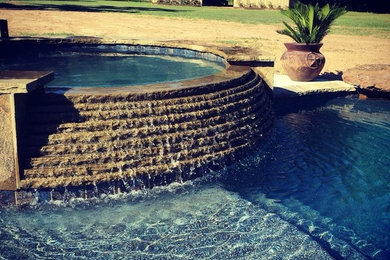 Imagen de piscinas y jacuzzis alargados clásicos grandes a medida en patio trasero con adoquines de piedra natural