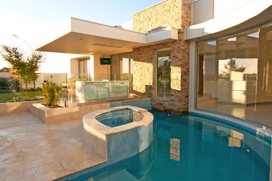 Foto de piscinas y jacuzzis actuales de tamaño medio a medida en patio trasero con adoquines de piedra natural