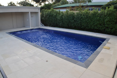 Diseño de piscina contemporánea rectangular en patio trasero con adoquines de piedra natural