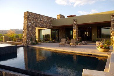 Modelo de piscinas y jacuzzis alargados actuales grandes rectangulares en patio trasero con adoquines de piedra natural