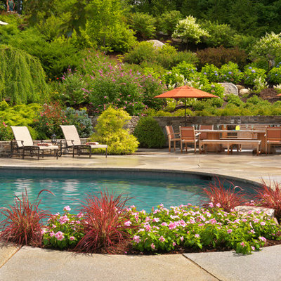 Large elegant backyard concrete paver and custom-shaped pool fountain photo in Boston