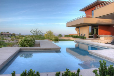 Imagen de piscina alargada de tamaño medio rectangular en patio trasero con adoquines de hormigón