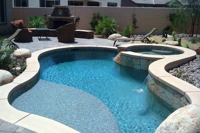 Modelo de piscinas y jacuzzis naturales exóticos de tamaño medio a medida en patio trasero con adoquines de ladrillo
