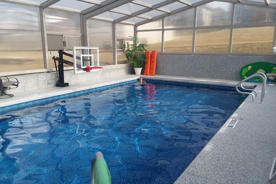Foto de piscina alargada actual grande interior y rectangular con losas de hormigón