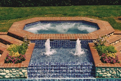 Example of a backyard stone and custom-shaped hot tub design in Other