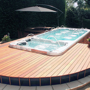 Immagine di una piscina moderna rettangolare di medie dimensioni e dietro casa con una vasca idromassaggio e pedane