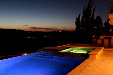 Diseño de piscina natural moderna de tamaño medio rectangular en patio trasero con adoquines de hormigón