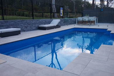 Foto de piscina alargada minimalista de tamaño medio rectangular en patio trasero con adoquines de hormigón