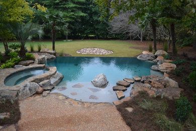 Esempio di una piscina naturale personalizzata di medie dimensioni e dietro casa con una vasca idromassaggio e pavimentazioni in pietra naturale