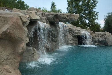 Example of a huge island style backyard stone and custom-shaped natural water slide design in San Diego