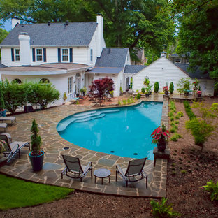 Design ideas for a mid-sized tropical backyard custom-shaped lap pool in Other with a hot tub and natural stone pavers.
