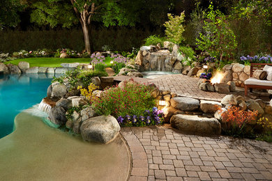 Imagen de piscina con fuente natural clásica renovada grande a medida en patio trasero con adoquines de ladrillo