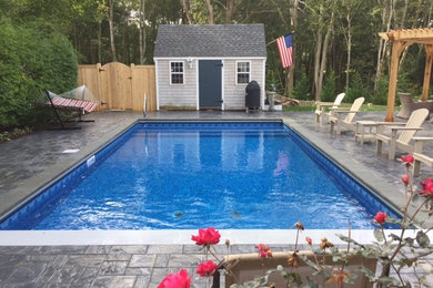 Modelo de piscina alargada clásica grande rectangular en patio trasero con suelo de hormigón estampado
