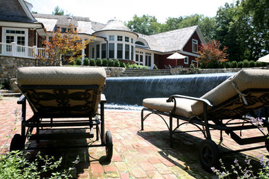 Пример оригинального дизайна: большой бассейн-инфинити произвольной формы на заднем дворе в классическом стиле с фонтаном и мощением клинкерной брусчаткой