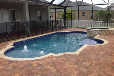 Modelo de piscinas y jacuzzis alargados tradicionales de tamaño medio a medida en patio trasero con adoquines de hormigón