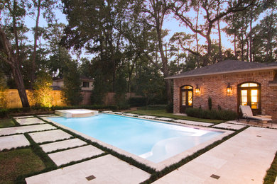 Ejemplo de piscina clásica de tamaño medio rectangular en patio trasero con adoquines de piedra natural