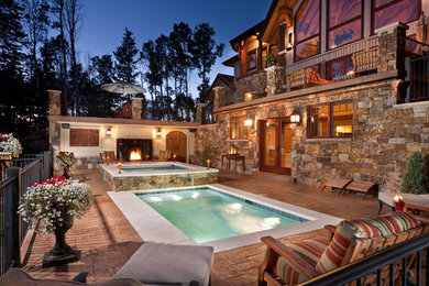 Modelo de piscinas y jacuzzis alargados de estilo americano grandes rectangulares en patio trasero con adoquines de piedra natural